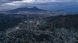 An aerial shot of El Salvador, with mountains in the distance and houses on the ground.