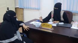 Сотрудница ЮНФПА сидит за столом и объясняет посетительнице о вреде калечащих операций