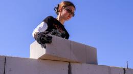 Молодая женщина в солнечных очках на стройке двигает бетонный блок