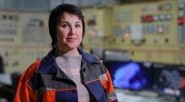 Женщина в спец одежде на фоне пульта управления электростанцией