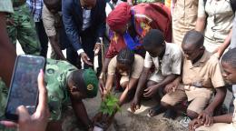 Un groupe de personnes plantant un arbre avec une jeune fille au milieu.