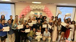 A group of people holding certificates in front of a banner and under a baloon arch
