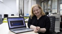 A woman seated at a computer looking at the camera