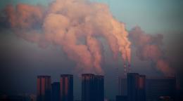 A picture of chimneys billowing smoke out in a city