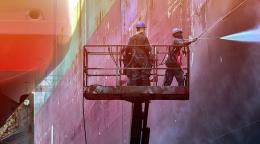 Two workers cleaning a container ship