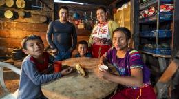 A family sits around a table, they are looking at the camera and smiling