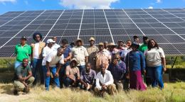 A group of people standing in front of a panel of solar panels