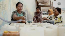 A group of women fill containers with water through pipes
