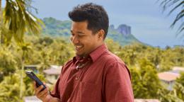 A man in Micronesia happily looks at his cell phone.