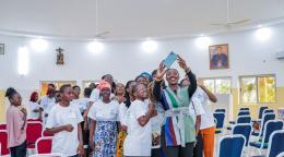 A high-level official in Togo takes a photo with female high school students.