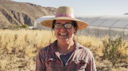 A female Chilean farmer stands on her land.