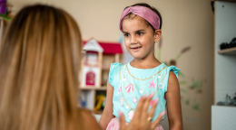 Девочка смотрит на социального работника и улыбается.