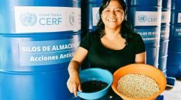 A woman in Guatemala holds two bowls full of her harvests.