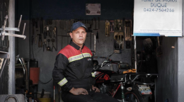 En el estacionamiento de su casa, Gerald Josué Duque ajusta un motor.