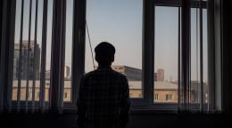 Мужчина смотрит в окно на город