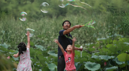 A man and his two daughters in China play with bubbles.