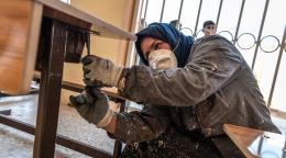 A woman in Iraq fixes a desk in a school.