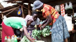 Three women in Uganda sell fresh vegetables as part of their agribusiness.
