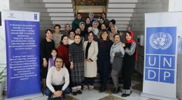 Группа людей позирует для совместной фотографии рядом с баннерами ПРООН.