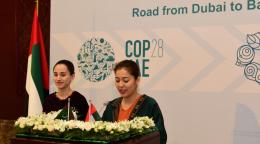 Две девушки выступают с речью за трибуной, украшенной цветами.