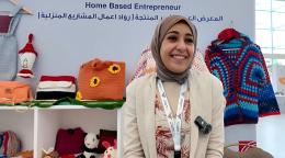 A woman at a conference in Bahrain shows her entrepreneurial work, such as bags and a top.