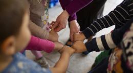 A group of kinds in Poland join fists in a circle.