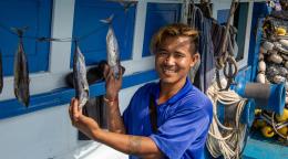 A migrant fisher in Thailand holds his catch