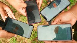 Several hands each hold a cell phone.