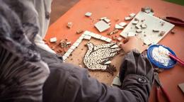 A woman makes a mosaic dove.