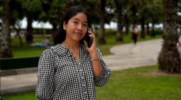 Una mujer joven sonríe mientras habla por teléfono en un parque.