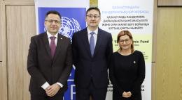 Три представителя сфотографированы на фоне плакатов.