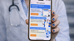 A doctor holds a phone displaying an e-health app.