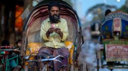 Un homme compte les gains de sa journée sur son rickshaw à Dhaka, au Bangladesh.