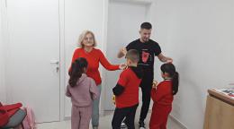 Two adults interact with three children at a community centre in Albania.
