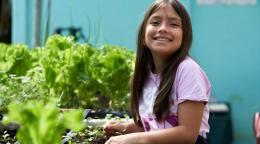 Una niña en Costa Rica frente a un pequeño jardín.