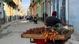 A man in Cuba rolls his fruit stand.