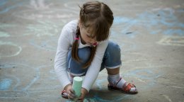 A girl in Moldova draws on the ground with chalk.