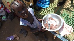 A girl in South Sudan holds a bowl of food.