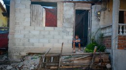 Un niño está sentado frente a su casa en Cuba.