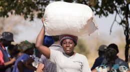 A woman in Namibia carries a bag of food on her head.