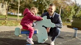 A man and his young daughter at a playground in Montenegro.