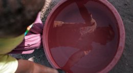 A child in South Sudan sees his reflection in a bucket of water.