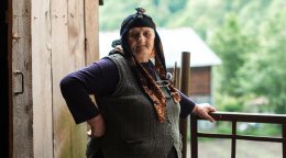 Женщина опирается на забор.