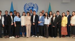 Делегаты фотографируются на фоне символики ООН