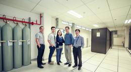 Five people stand together smiling at the camera. 