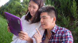 Two people look at a purple tablet. 