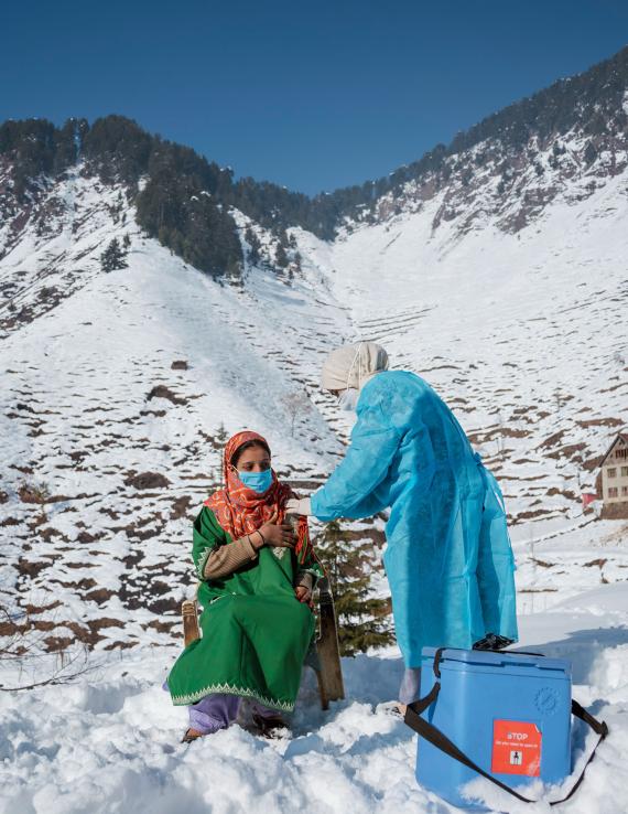 A woman gets vaccinated against COVID-19 on a snowy mountain top.