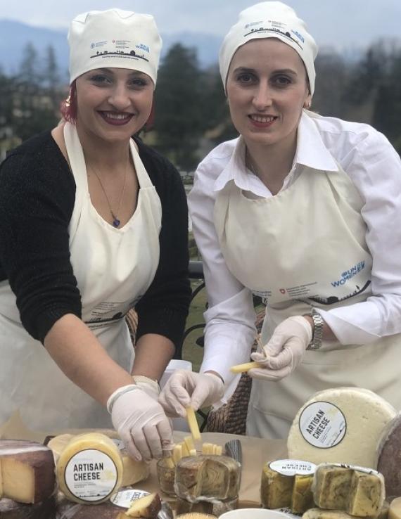 Two women selling cheese in an outdoor setting