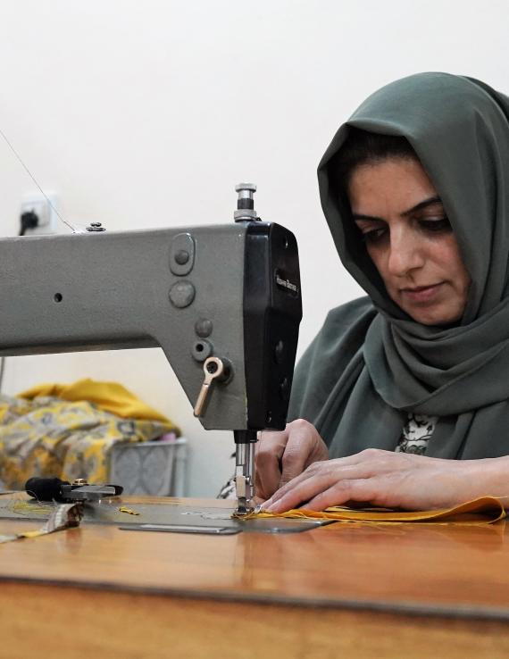 شابة في العراق تستخدم ماكينة خياطة