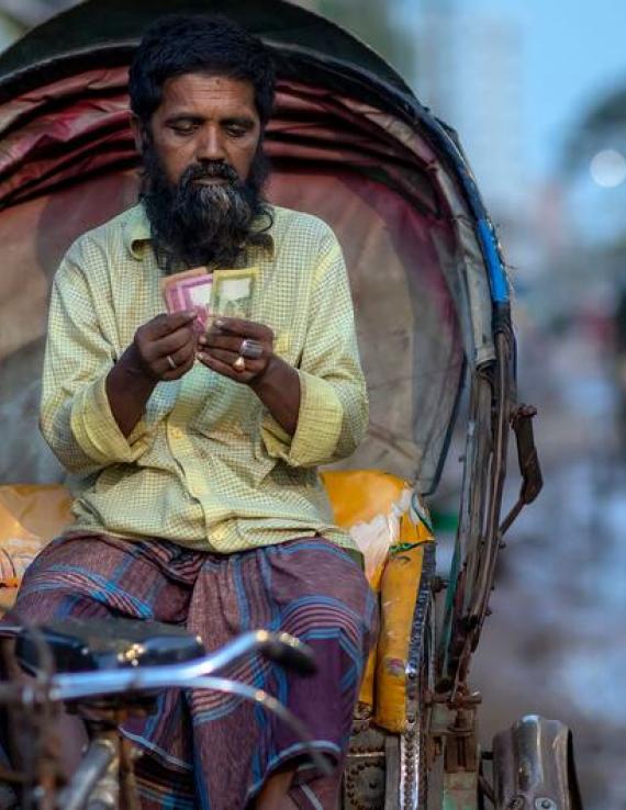 Un homme compte les gains de sa journée sur son rickshaw à Dhaka, au Bangladesh.